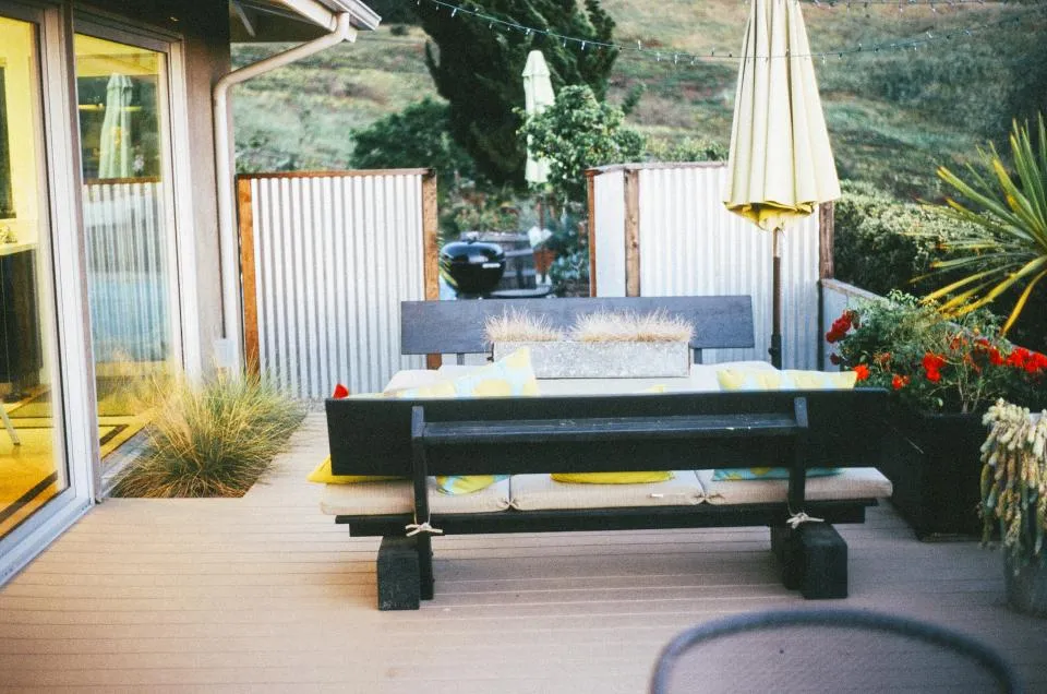 A wooden backyard deck with patio furniture and cushions, the kind of gear a large deck box is bought to store