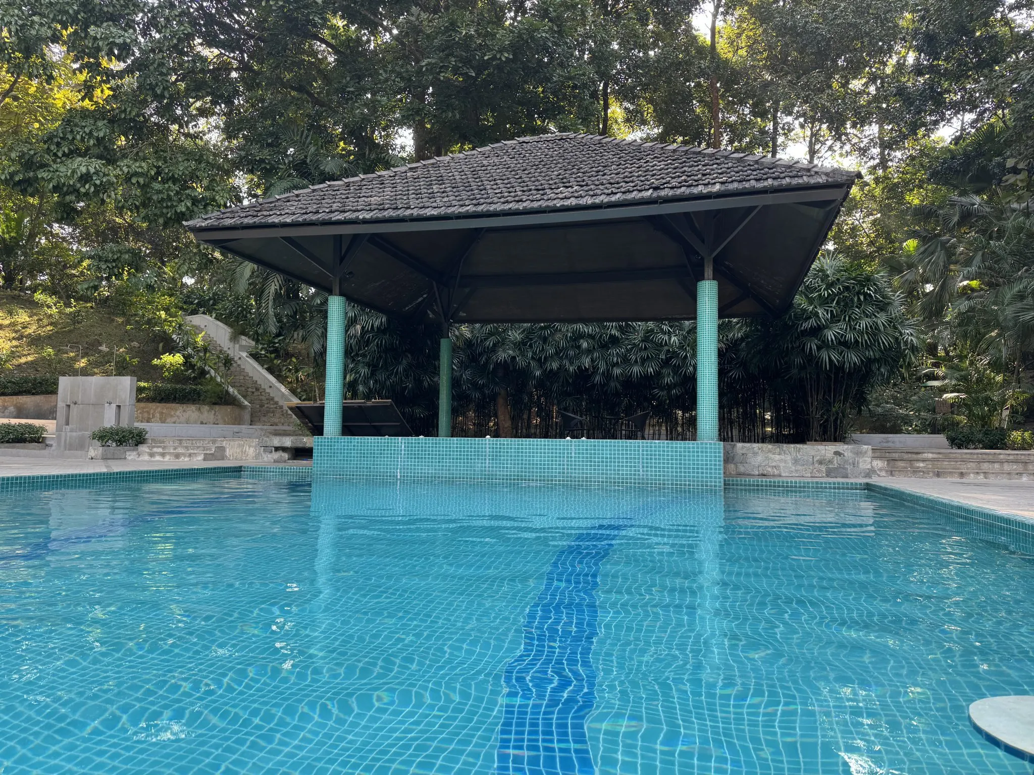 A shaded outdoor structure over a patio beside a swimming pool