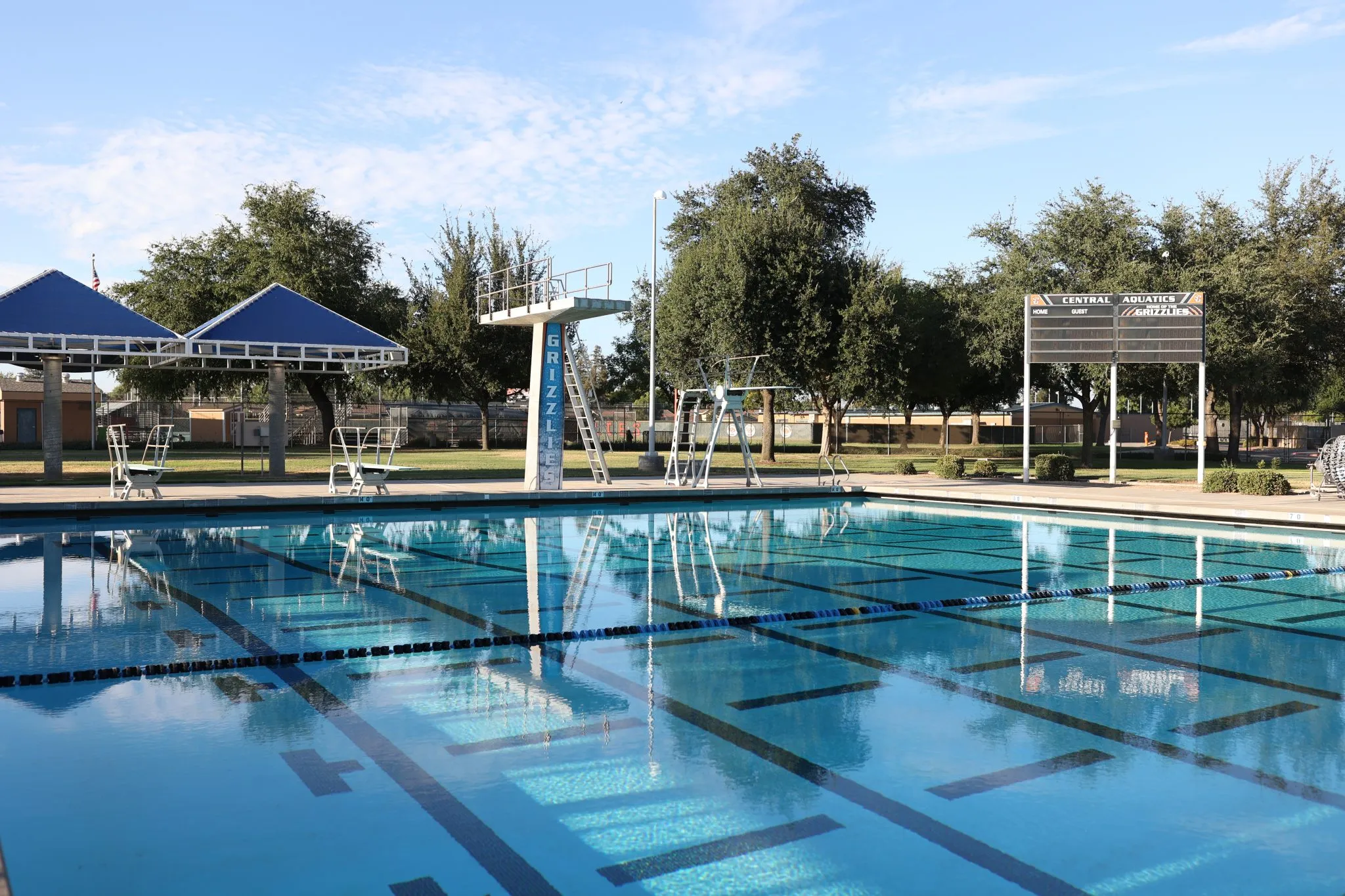 A clear blue in-ground swimming pool on a bright day