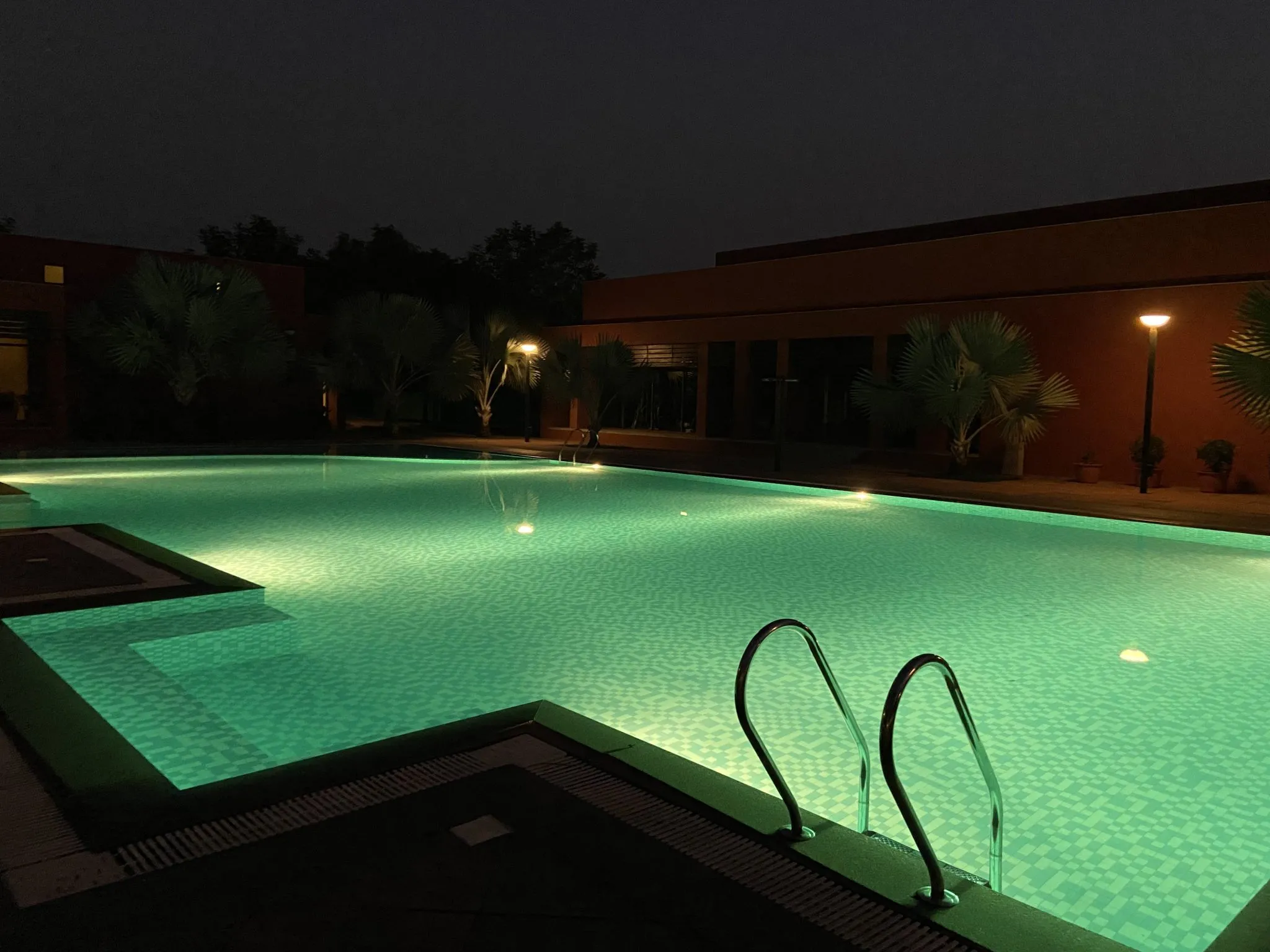 A backyard pool glowing with color-changing floating lights on the water at night