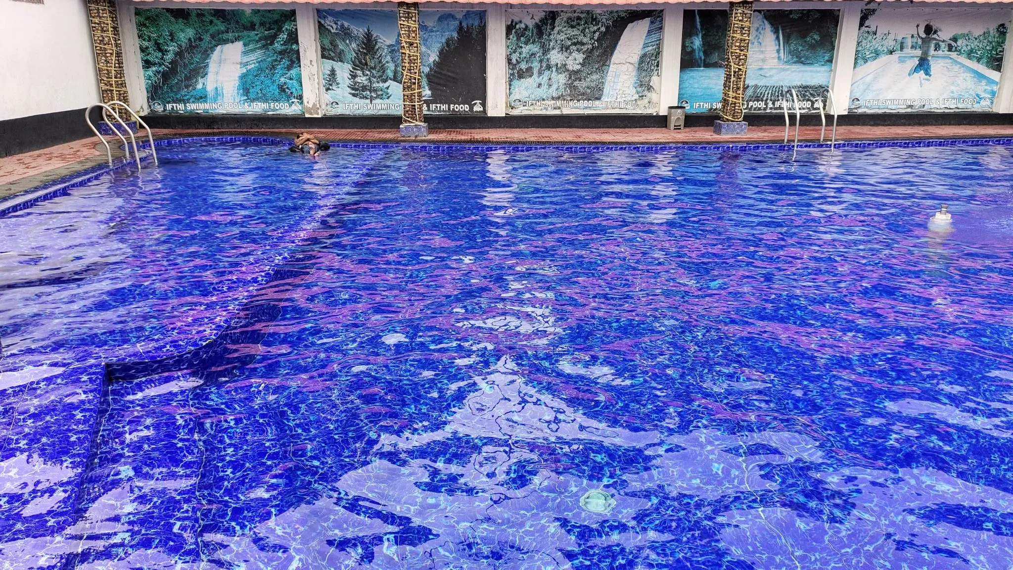 A wide turquoise in-ground swimming pool on a sunny day