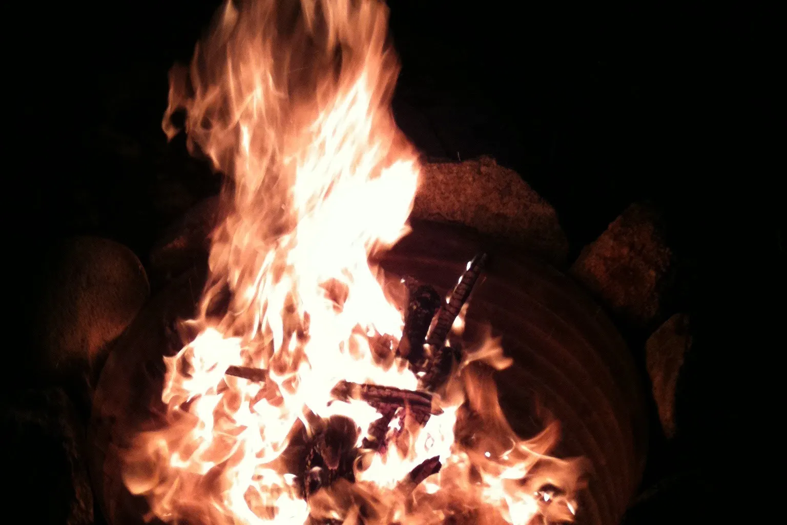 A roaring fire in a stone fire pit at night